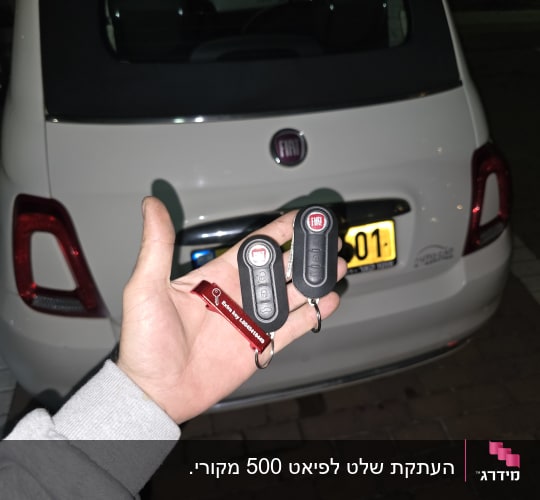 מפתחות רכב פיאט ביד מול רכב לבן